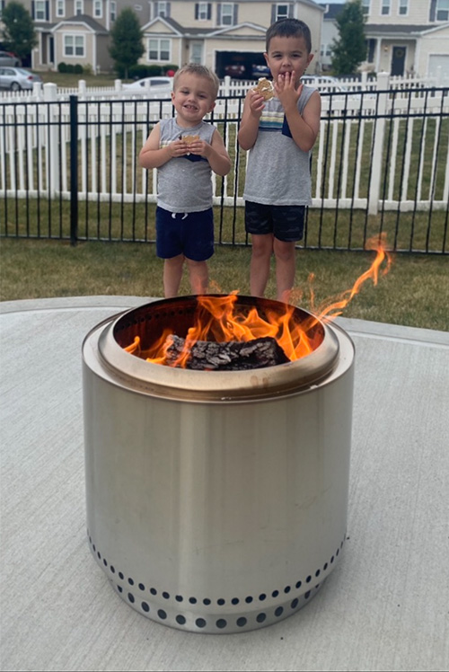 Win Fire Pit - Fire Pit Currently Lit with Children Standing Behind it in a Neighbor Hood
